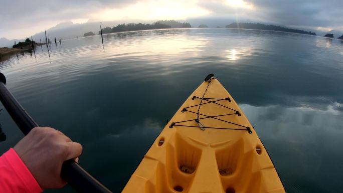清晨在阳光下在热带大湖中划皮划艇的女子pov。放松运动