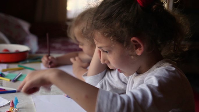 两个小女孩坐在桌子旁画画