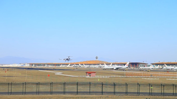 一架飞机从远处飞过又降落在飞机场内跑道上