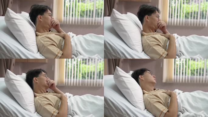 亚洲男性患者在医院休息时在床上打喷嚏。