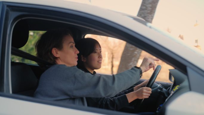 女驾校教练正在教年轻女子如何开车。