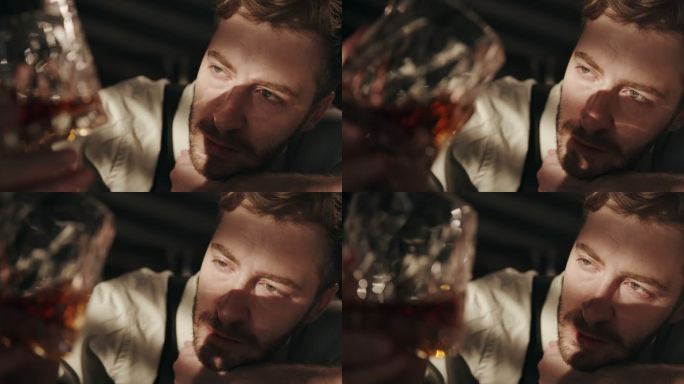 一个醉汉若有所思地看着一杯威士忌的特写镜头，他在一个黑暗的酒吧里一只手
