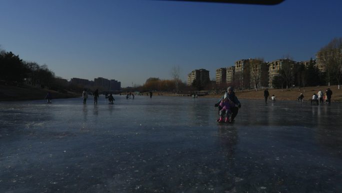 冬季冰湖上父女俩滑冰车