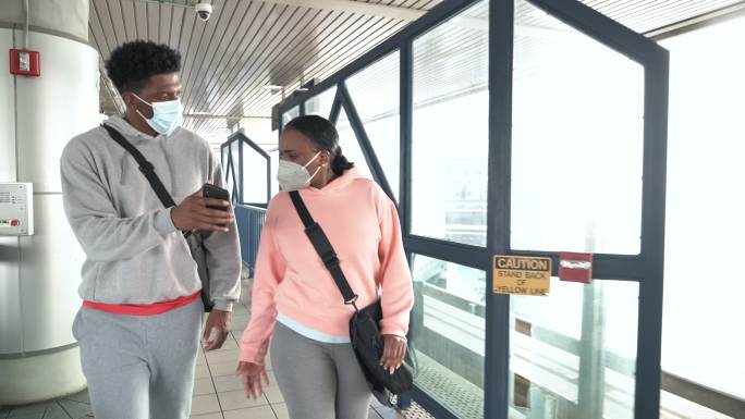 火车站台上戴着口罩的非裔美国人夫妇
