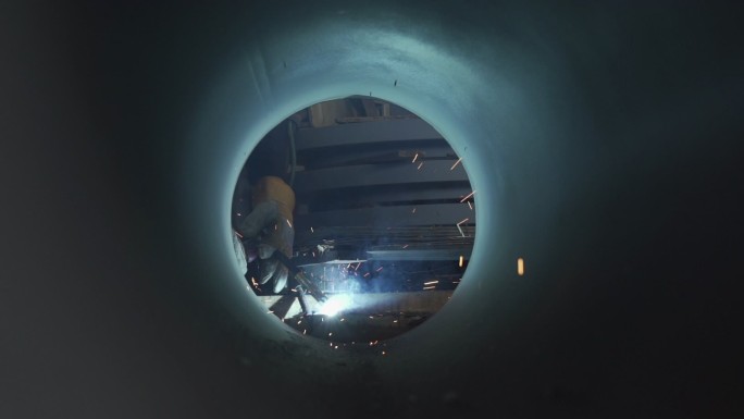 一名焊工正在通过一根大管道焊接金属摄像机角度