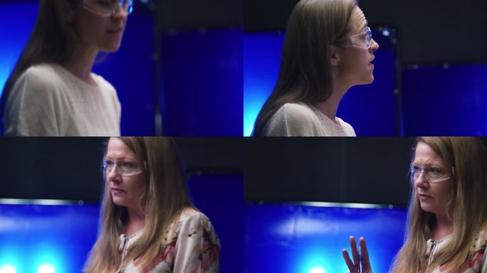 两名30多岁和40多岁的白人女性同事戴着安全眼镜，在室内制造工厂讨论一种铝制3D打印形状