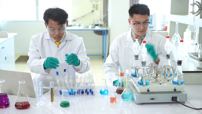 一名亚洲医学科学家小组的研究人员身穿实验服和防护设备，在寻找潜在的新冠肺炎疫苗时，仔细检查、测量和处