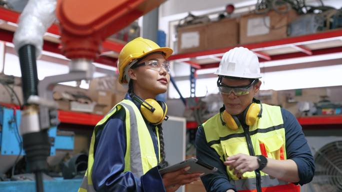 亚洲男性员工向新女性员工教授如何控制机器。