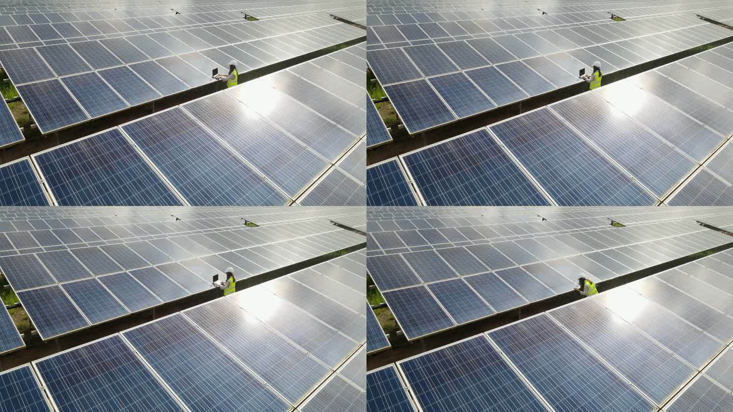 鸟瞰技术工程师走过太阳能电池板，检查太阳能发电场的太阳能电池板。