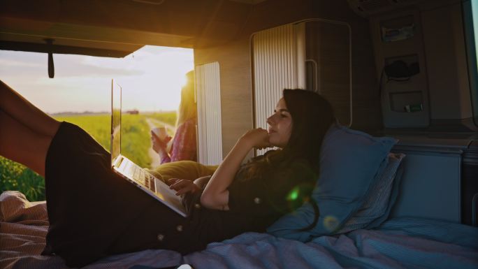 阳光明媚的一天，DS Woman在乡村露营车上使用笔记本电脑