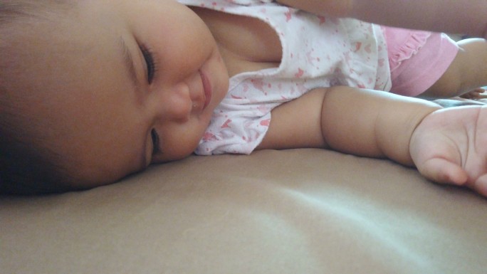 亚洲女婴躺在床上翻滚
