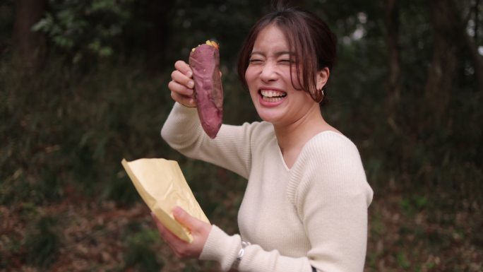 快乐的年轻女人散步和吃红薯