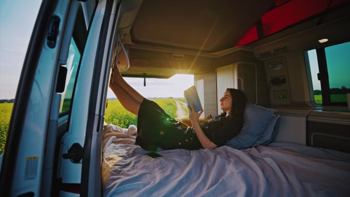 DS女子在阳光明媚的一天停在露营车的小屋里看书