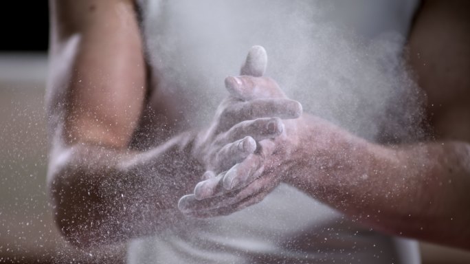 SLO MO体操运动员将健身粉笔擦在手上