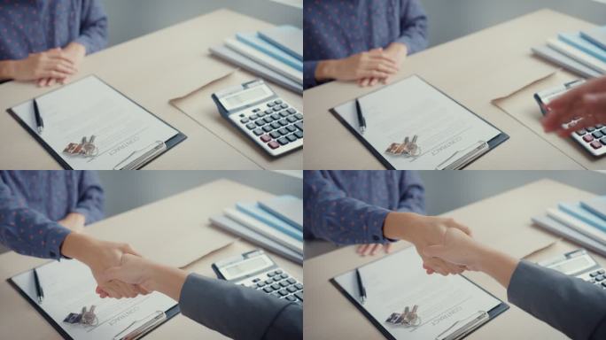 年轻的亚洲女商人在办公室签署合同后与房地产经纪人握手的特写镜头。