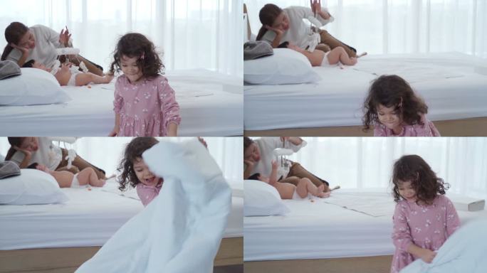 可爱的小女孩在卧室里用毯子玩躲猫猫游戏