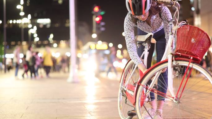 一个女孩晚上在城里锁自行车
