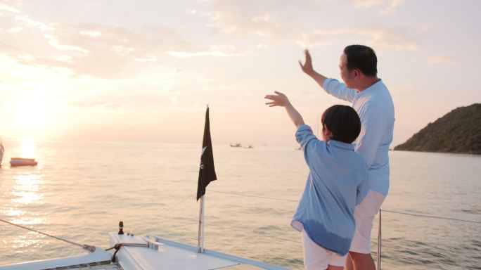 日落时分，父子俩在帆船上挥手致意