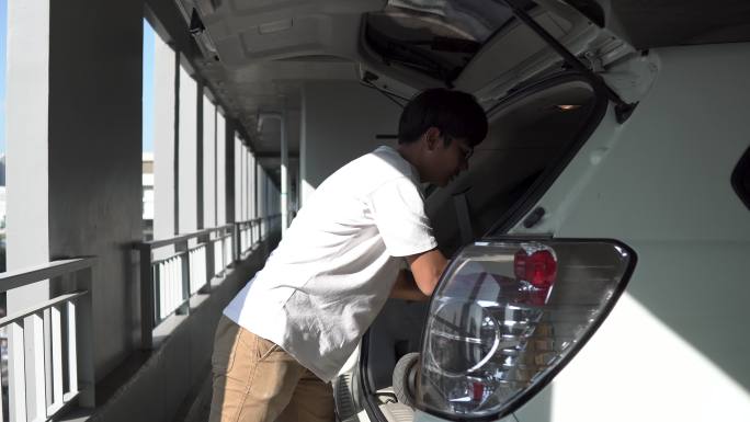 一名男子在汽车后备箱里携带电动滑板车。侧视图