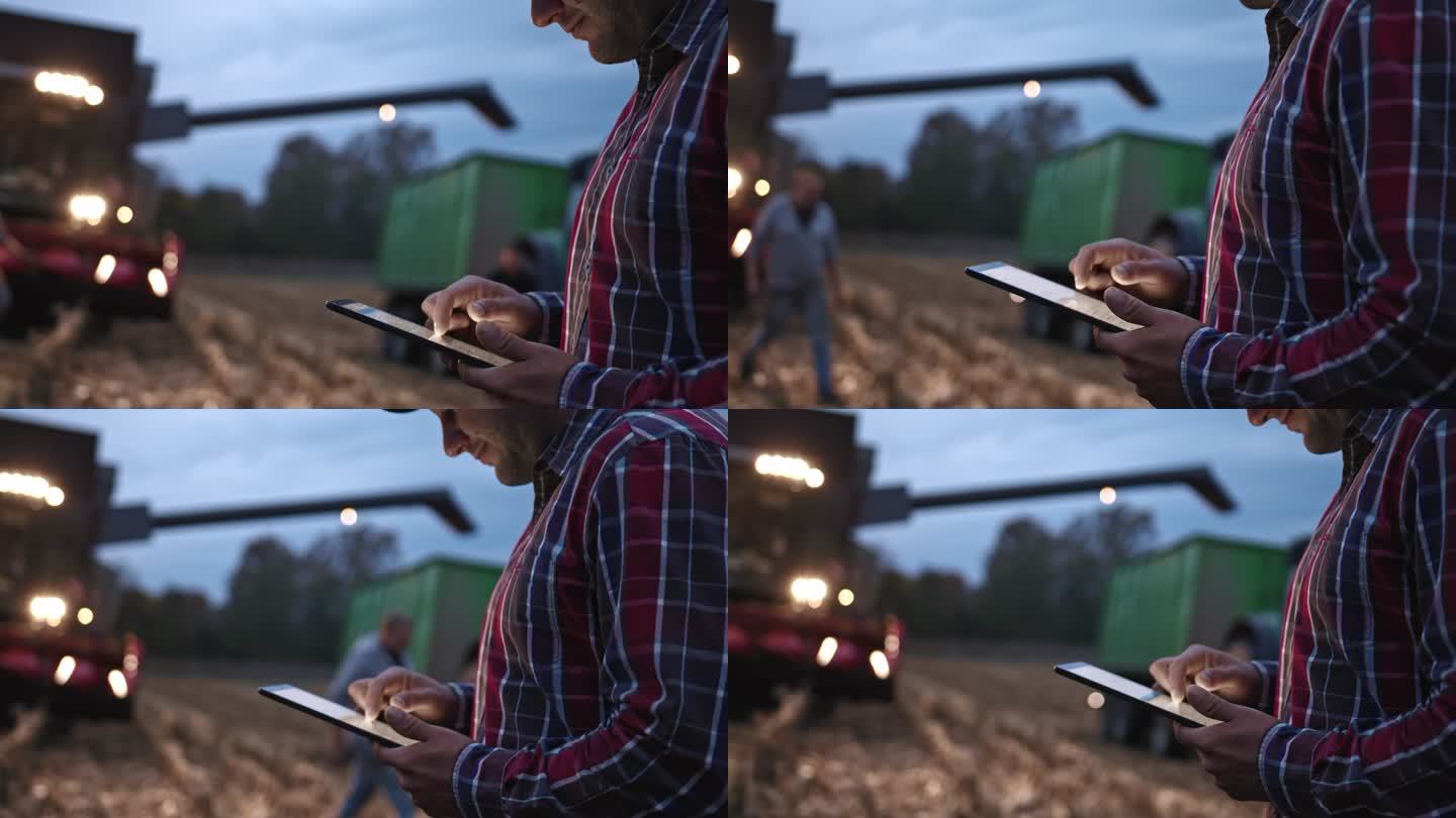 年轻人使用数字平板电脑和联合收割机在拖车上卸载玉米