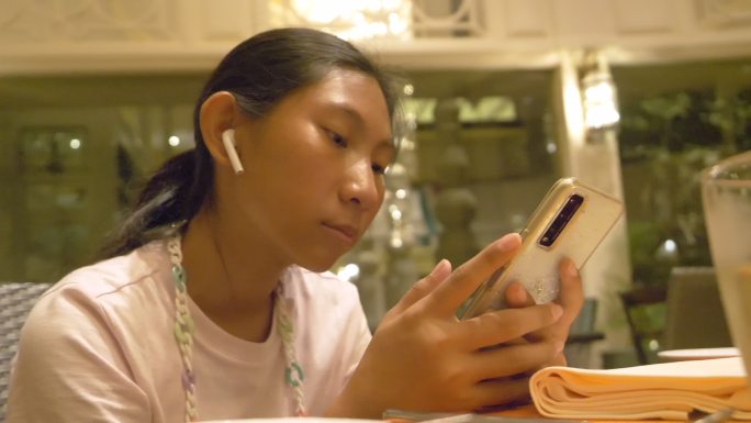 亚洲女孩在餐厅等待食物时使用智能手机，生活方式理念。