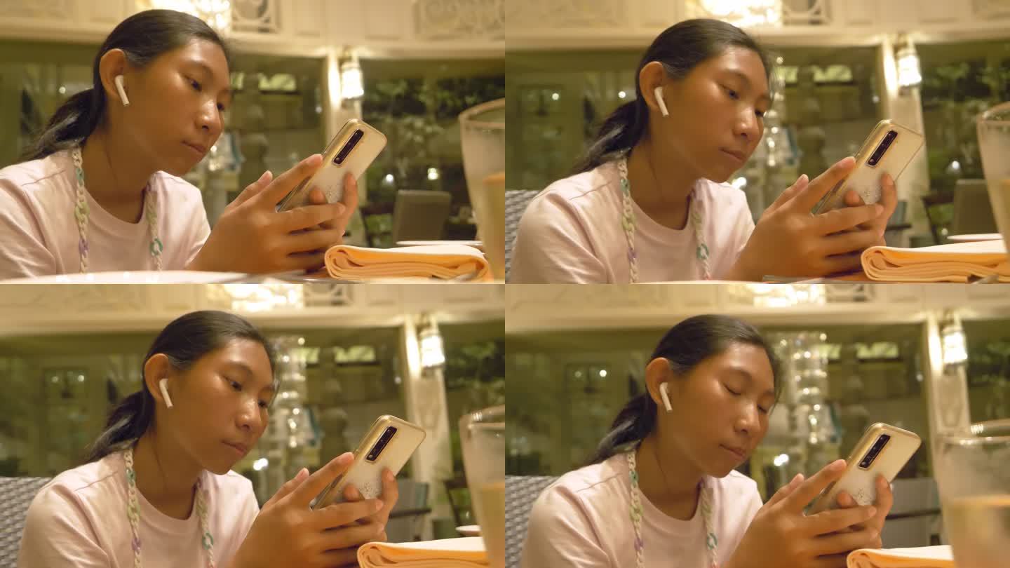 亚洲女孩在餐厅等待食物时使用智能手机，生活方式理念。