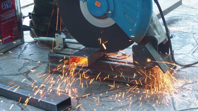 专业机械师正在使用旋转金刚石刀片切割机切割钢金属。钢铁工业和车间概念。