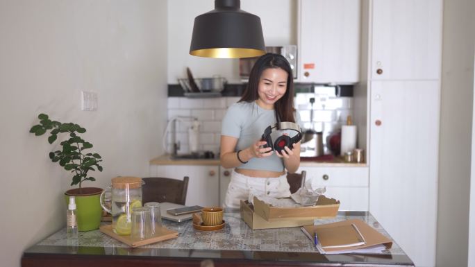 亚洲中国美女在厨房网购时戴耳机开箱