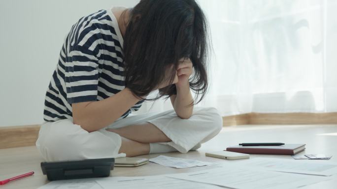 面对债务问题后，压力重重的女人捂着脸。亚洲女性经济困难。缺钱。过度信贷。处理财务问题。