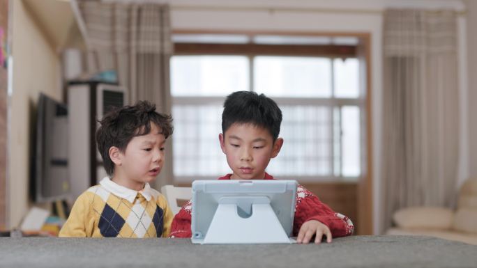 两个小男孩在桌上玩数字平板电脑