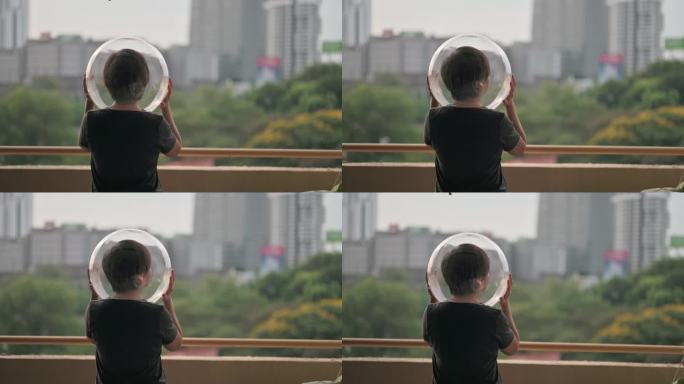 创意肖像后视图亚洲中国中年女性，戴透明全头盔，从阳台上看风景