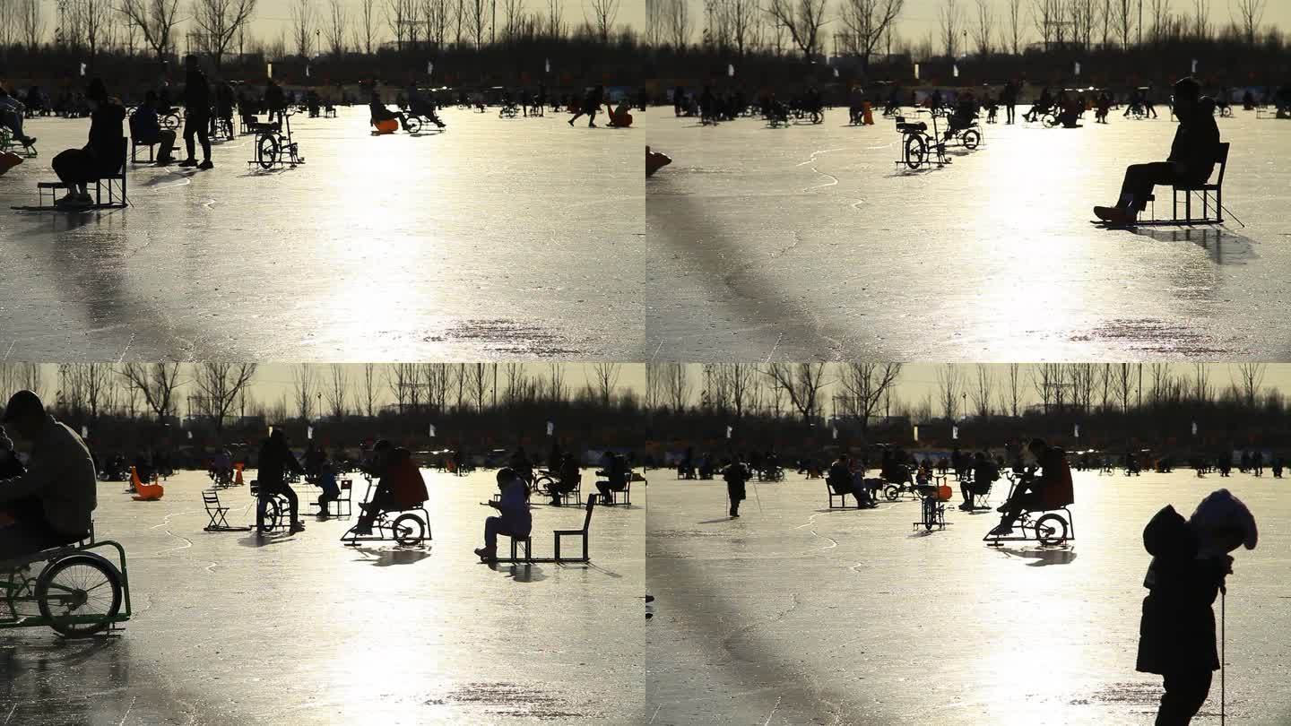 逆光拍摄冬季人们在冰上滑冰骑冰车