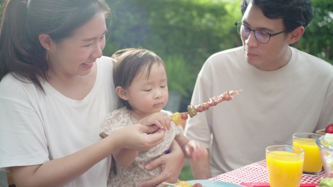 亚洲家庭晚上在家后院花园野餐时吃烧烤这是一个快乐的家庭假期。