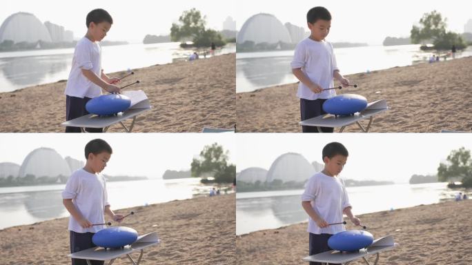 男孩在夕阳西下的海边沙滩上演奏空灵鼓