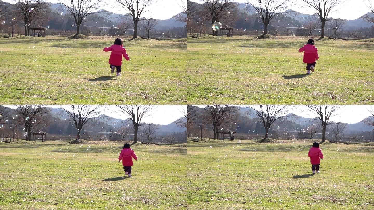 慢动作快乐快乐的亚洲小女孩在公园里玩泡泡肥皂。