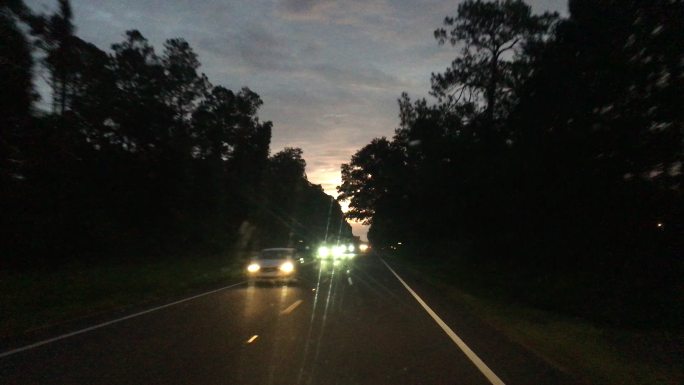 黎明前/夜间在有迎面而来车辆的农村铺面道路上行驶