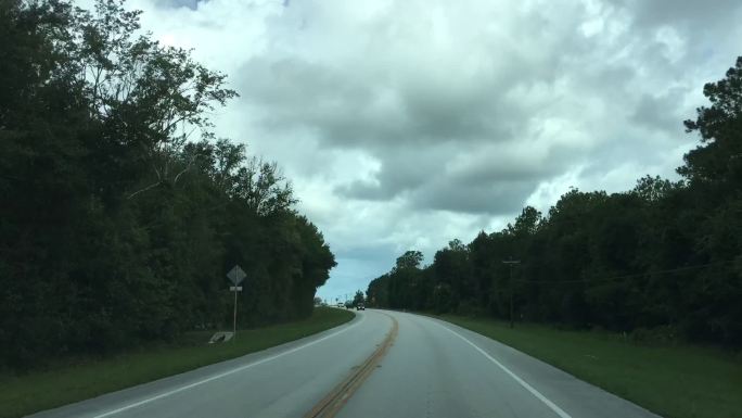 在佛罗里达州梅尔罗斯附近的一条弯弯曲曲的乡村道路上，夏日的流逝，乌云密布，右边是雨