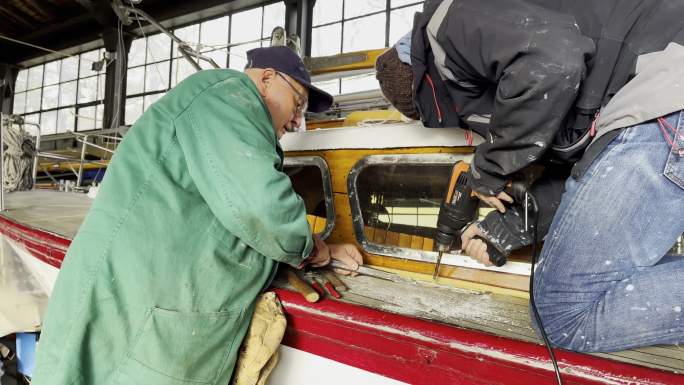 两名高级男子一起工作，在德国的帆船上进行维修工作