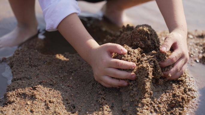 小男孩在河边的沙滩上挖沙子堆城堡