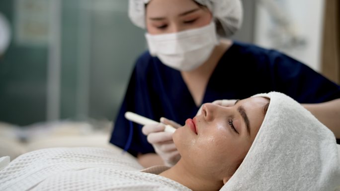 在美容诊所，女医生美容师在病人脸上打针。