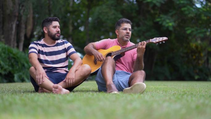 成熟的男人与朋友在后院弹吉他