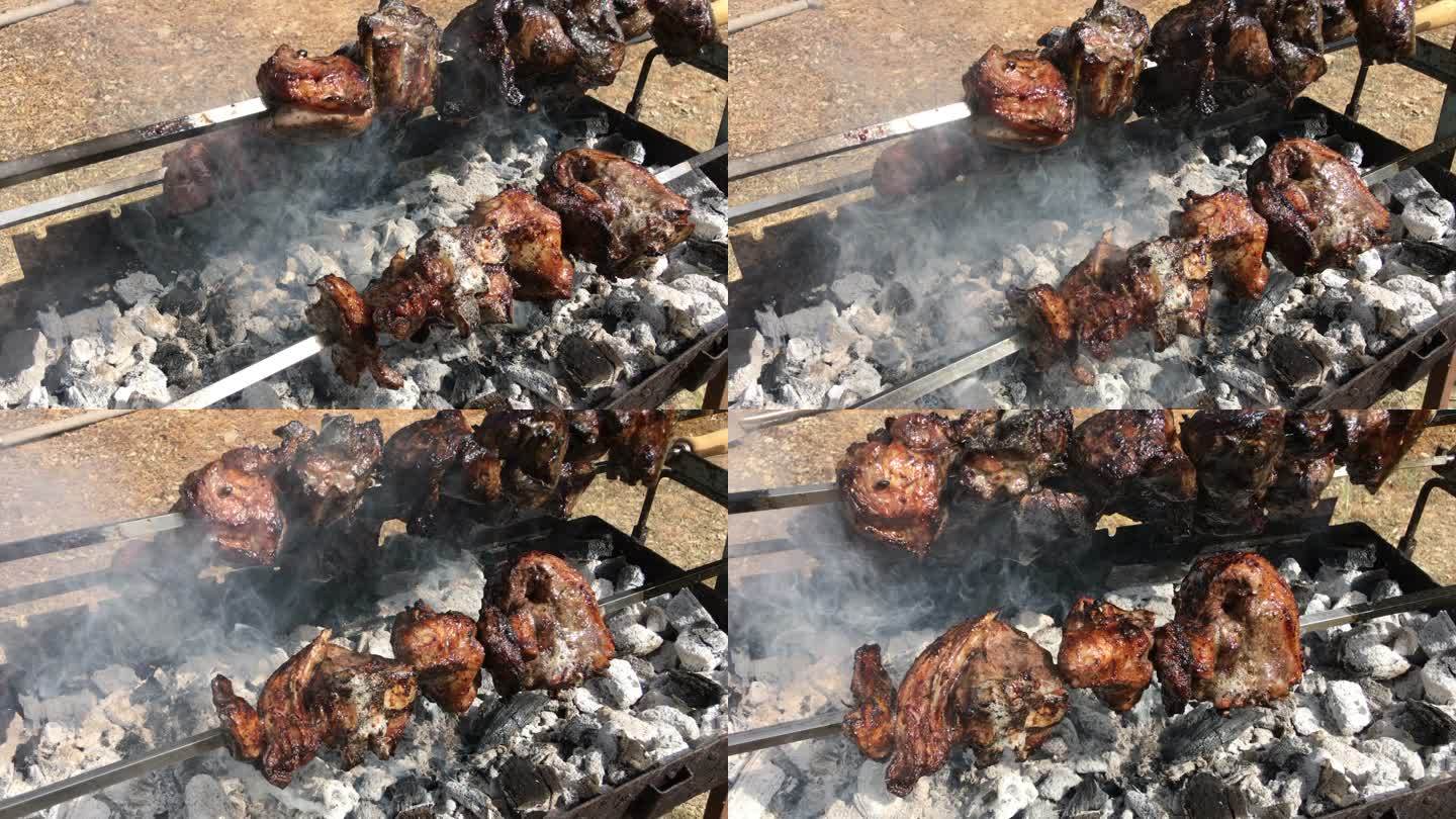 从右到左旋转拍摄三个厚厚的、缓慢旋转的烤羊肉串，烟雾从覆盖着灰烬的燃烧木炭中升起