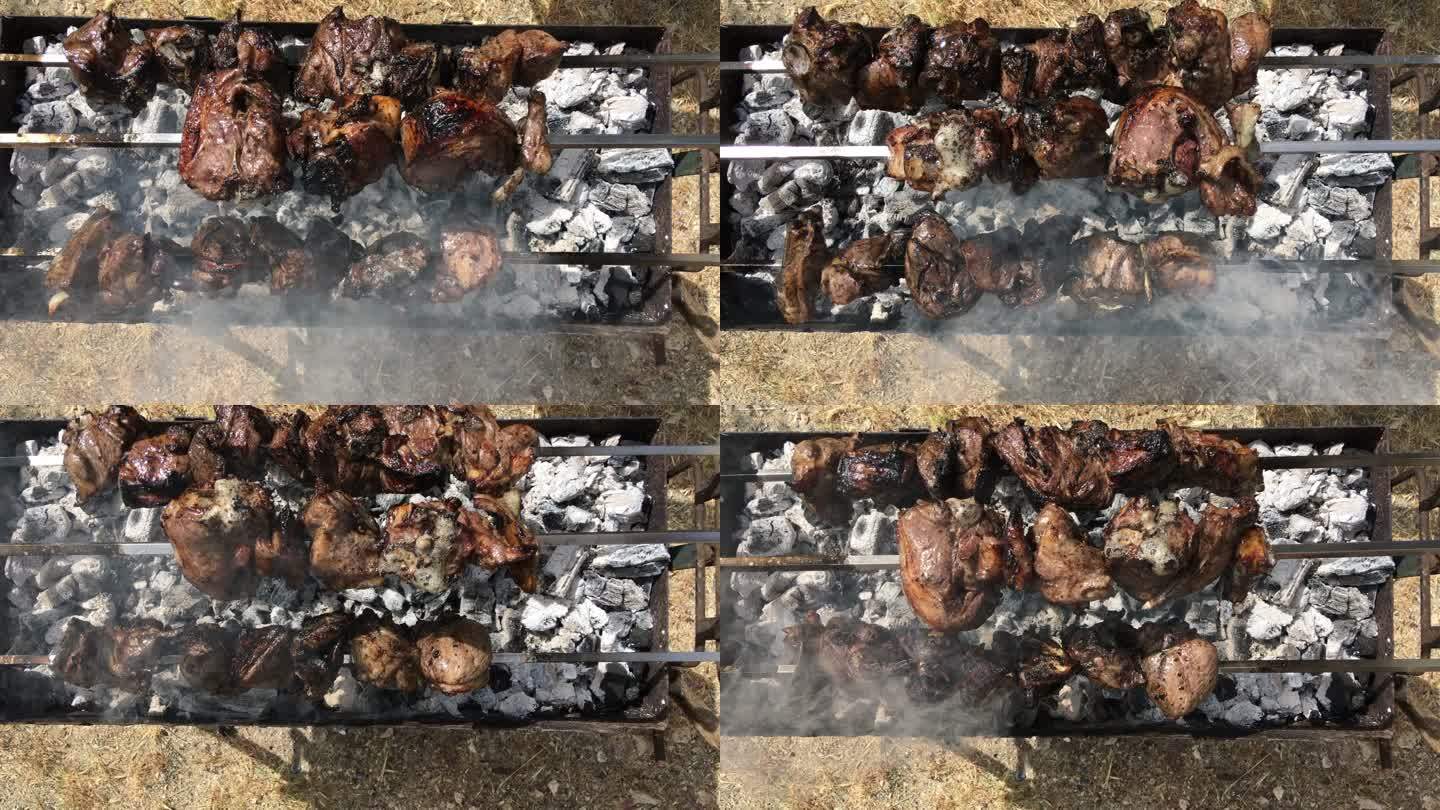 垂直拍摄三个缓慢旋转的烤串，烤羊肉，灰烬覆盖的燃烧木炭冒出缕缕烟雾