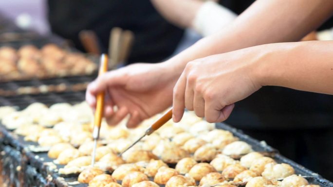 厨师们正在烹饪日本料理takoyaki，这是一种广受顾客欢迎的日本料理。