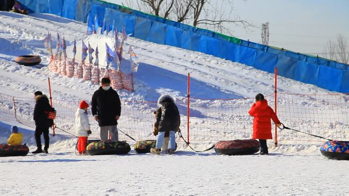 冬季滑雪场人们拉着轮胎依次排队等待滑雪
