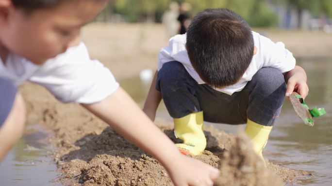 小男孩在河边的沙滩上挖沙子堆城堡