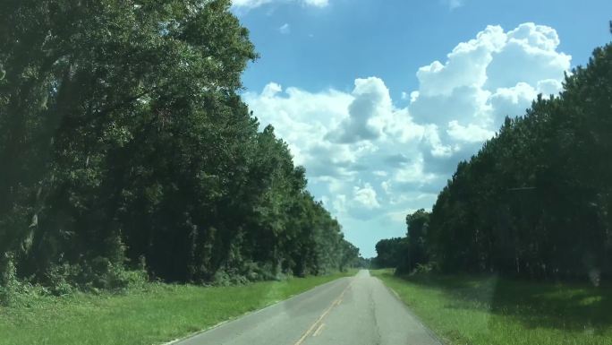 佛罗里达州布鲁克附近蜿蜒的乡村公路上行驶的超慢，天空中飘着遥远的夏季风暴云