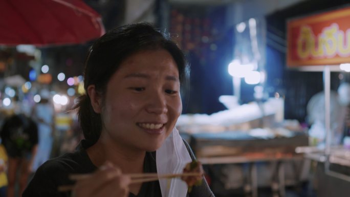 在夜市吃街头食品特写镜头筷子夹起展示旅行