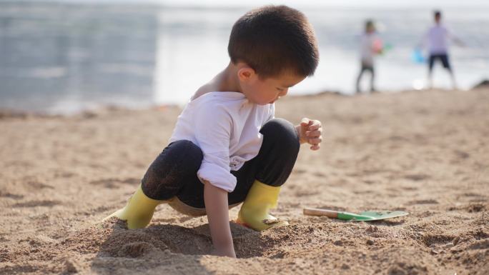 小男孩在河边的沙滩上挖沙子堆城堡