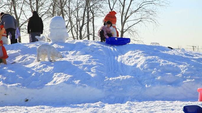 冬季滑雪场玩雪小孩从雪堆上滑下